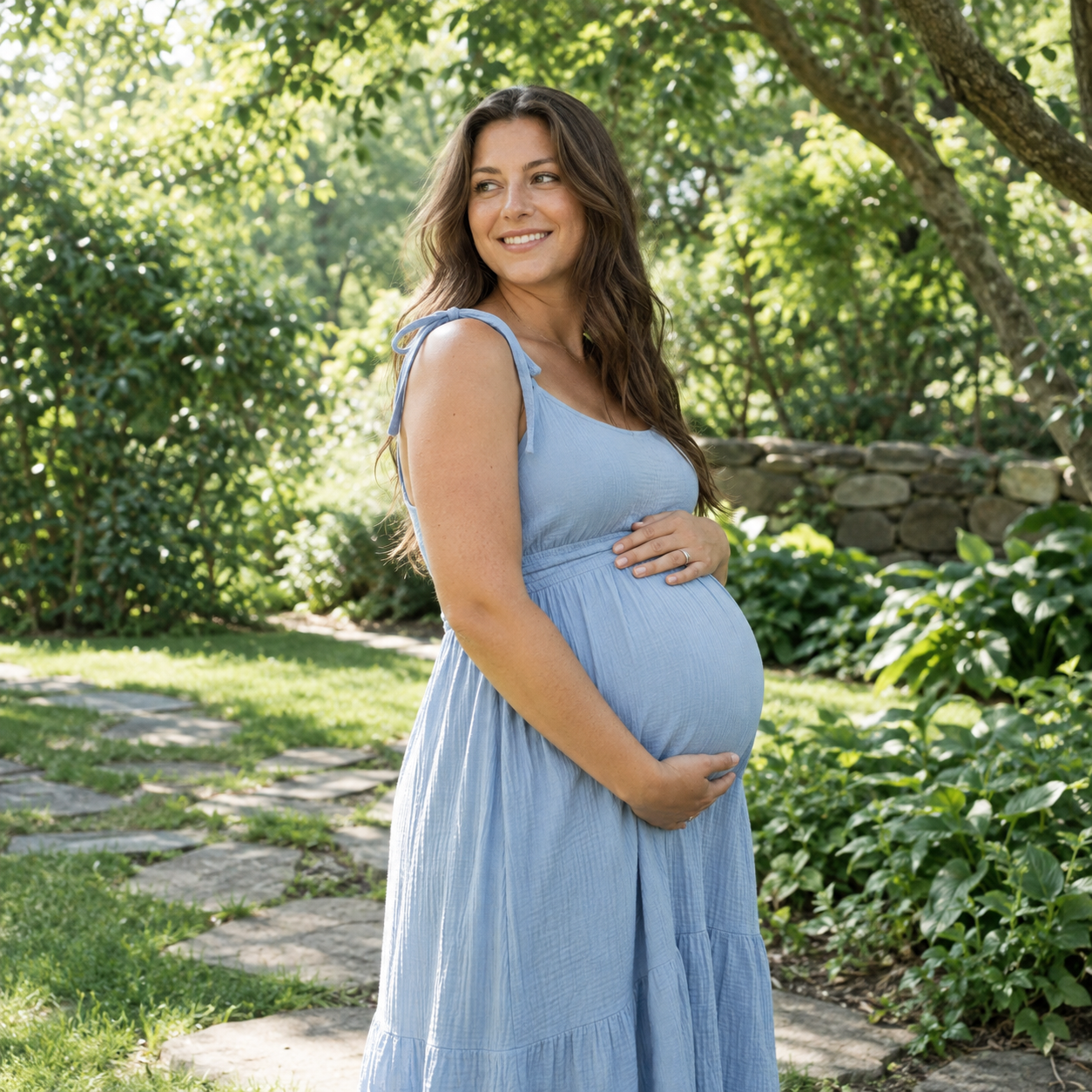 An expectant mother resting her hands on her belly in a green garden